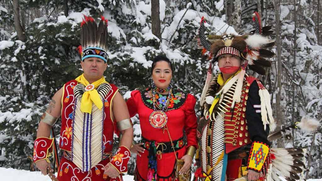 Three Native Americans standing in a snowy forest location