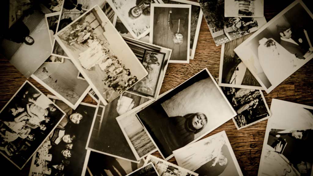 Black and white photographs of people scattered on a wooden surface