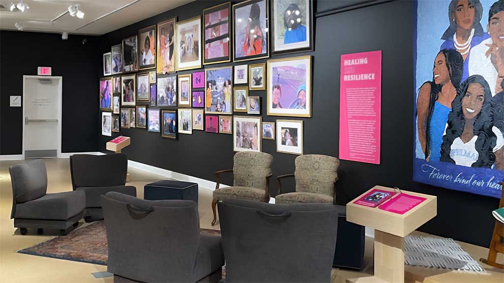 gallery space with circle of comfortable chairs in front of a wall packed with framed photos
