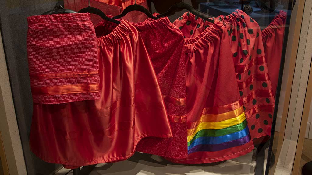 6 modern red garments (skirts and shirts) with various patterns in an exhibit case
