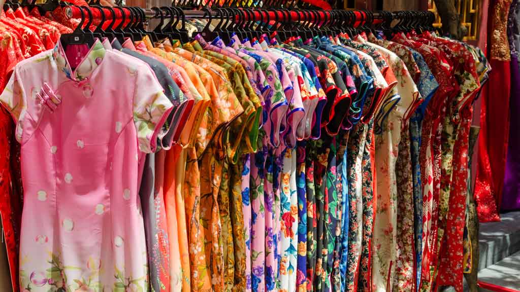 A rack full of colorful Chinese garments on a sunny day.