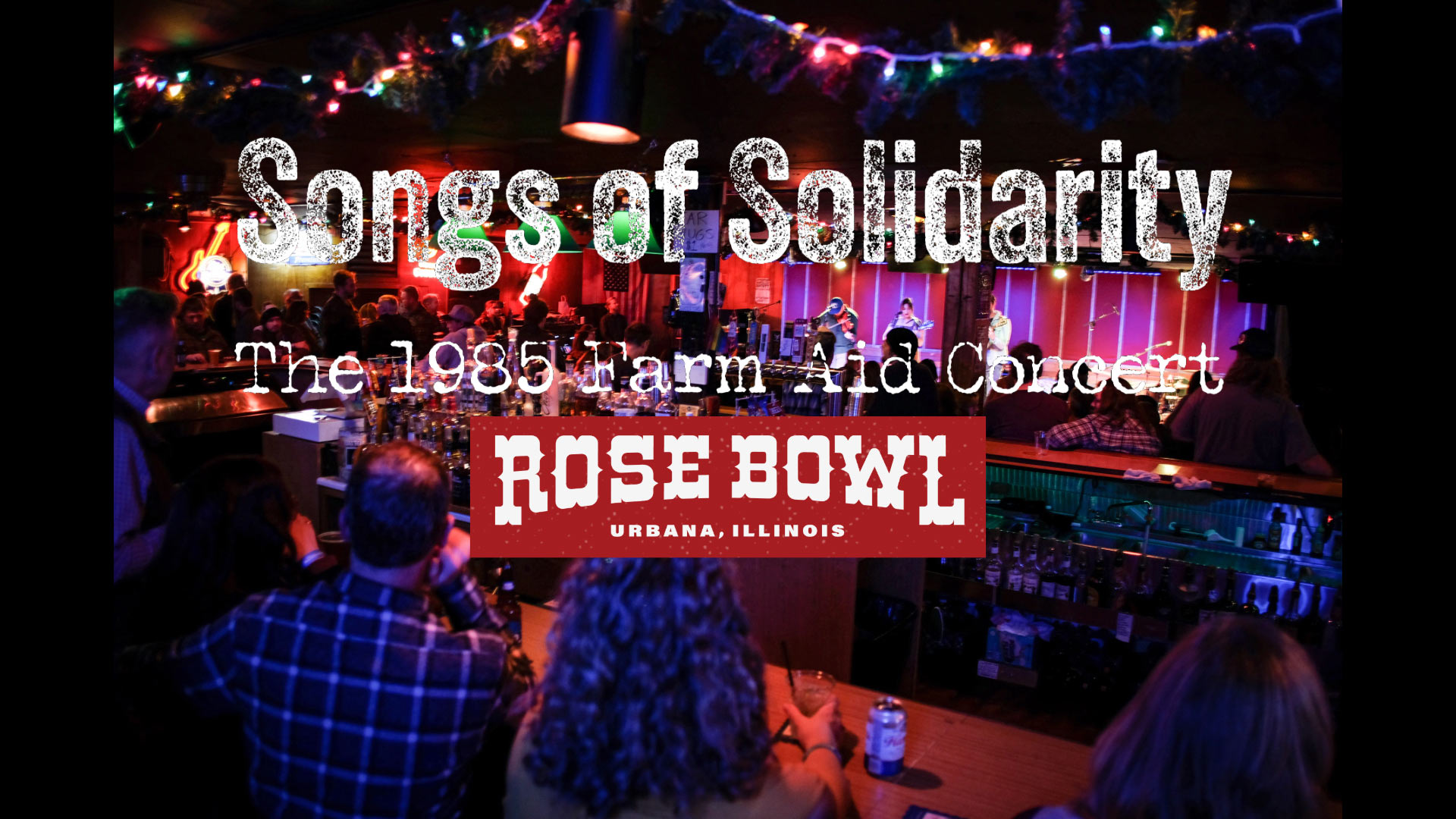 People in sitting at a bar decorated with twinkly lights watching a band play