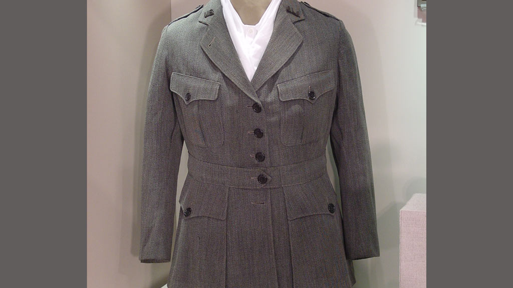A picture of an gray coat and white shirt on a museum mannequin.