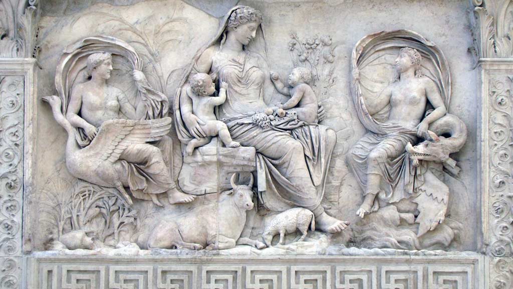 A old mural made of stone with a 3 woman and 2 kids sitting on chairs next to a bull and goat.
