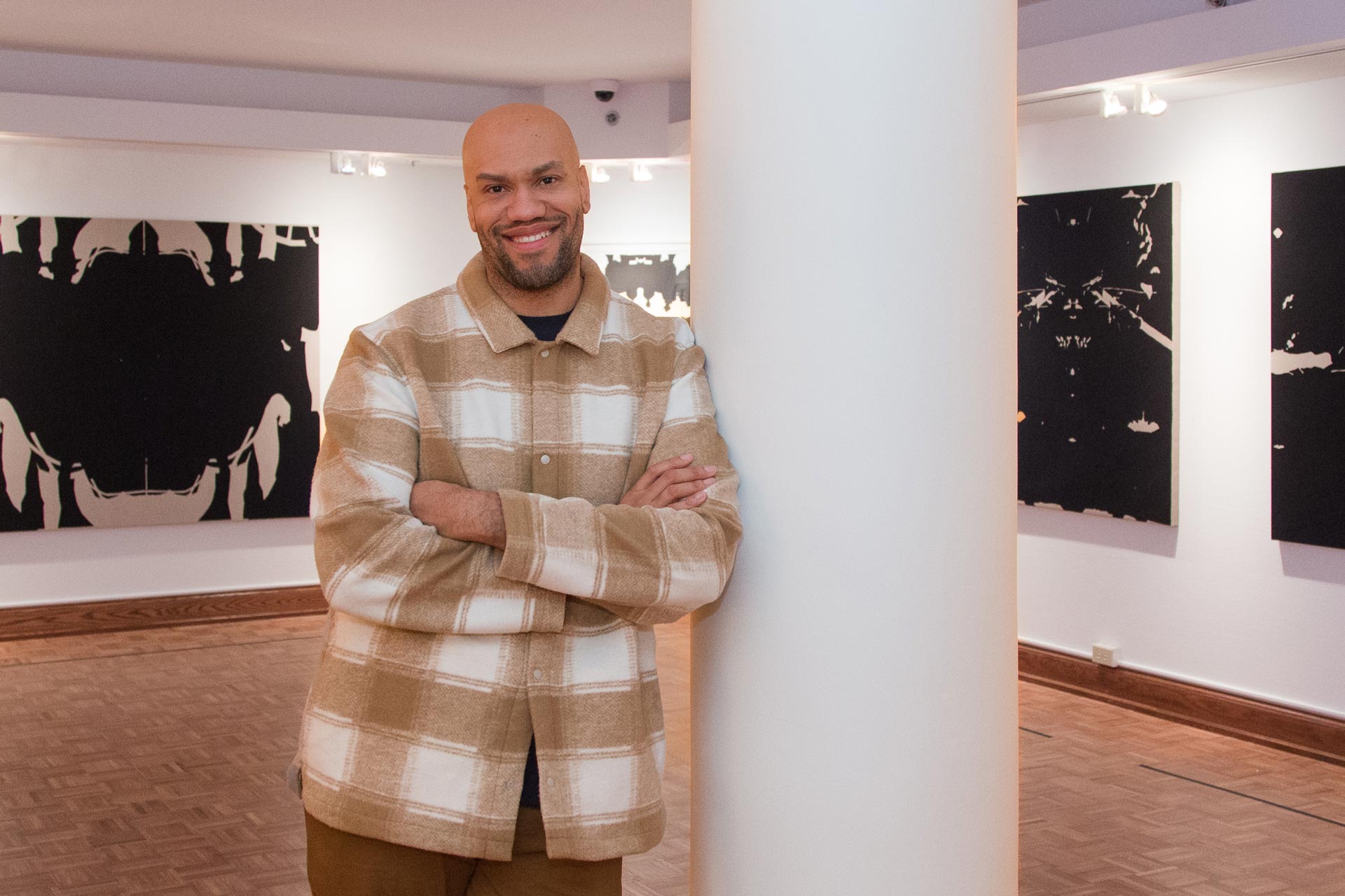 Smiling man in an art gallery leaning against a wall