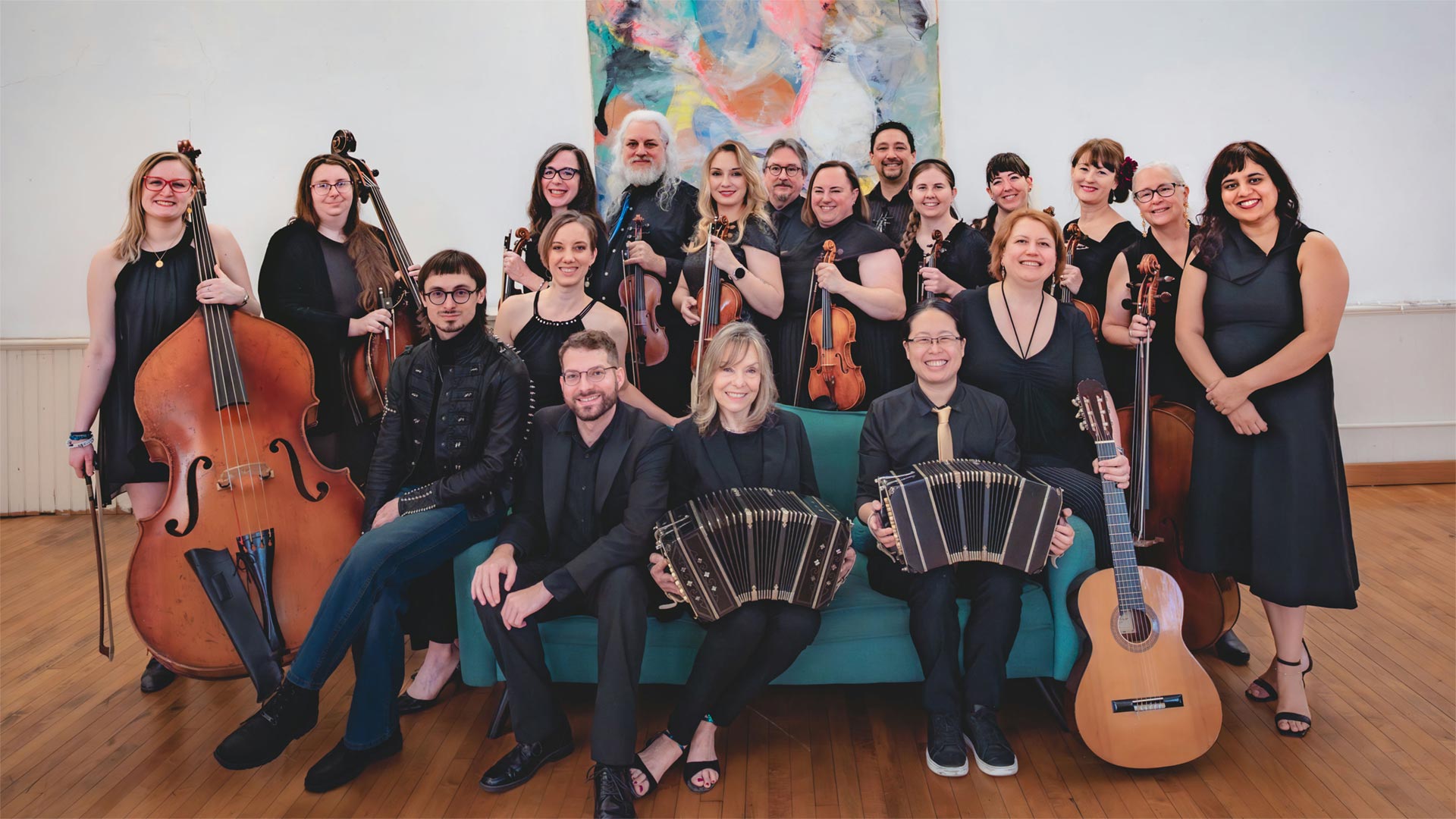 a group of about 20 musicians pose with accordians and stringed instruments
