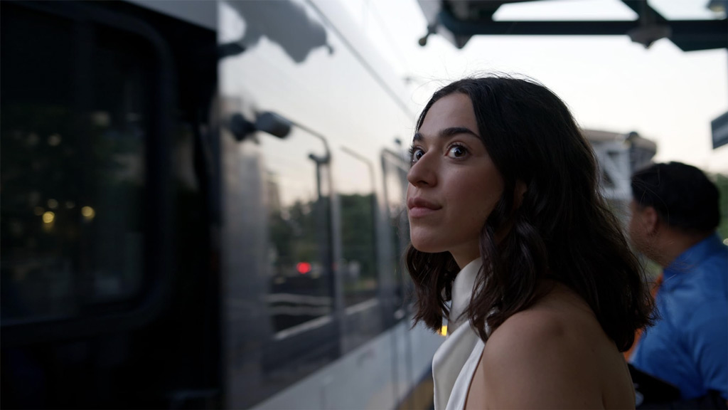 A woman facing a train on a train platform at daybreak or dusk