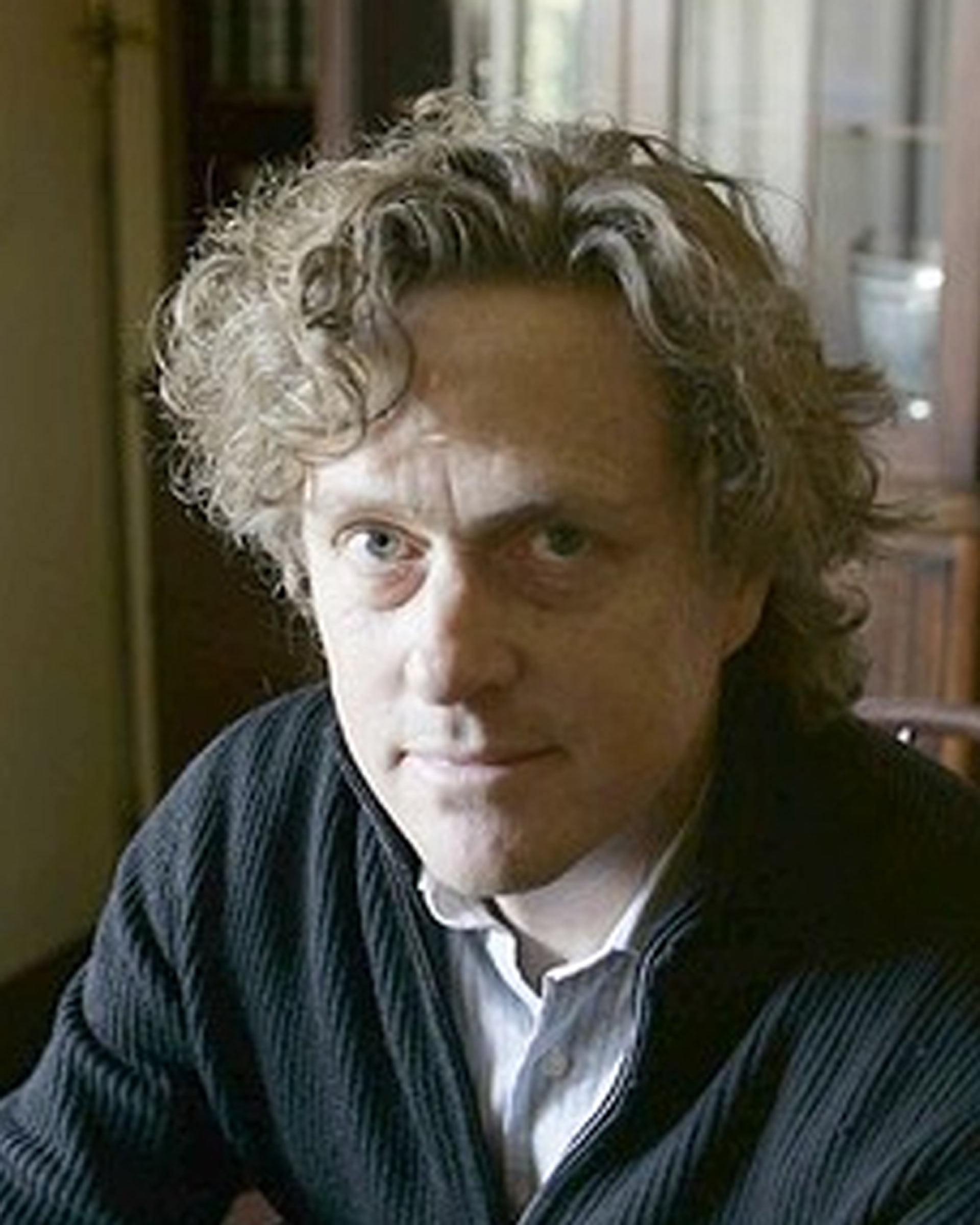 Headshot of a man smiling softly wearing a quarter-zip