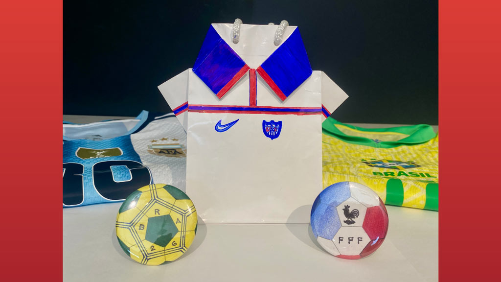 Three international football teams' uniforms with two footballs on a table
