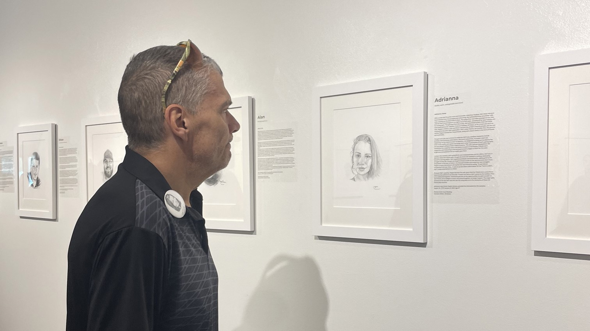 A man looking at a black and white poster with l=writing on the side of it.
