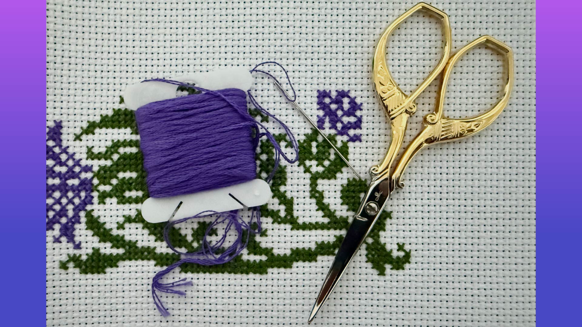 Stitching scissors and yarn laid over a woven cloth with a purple flower