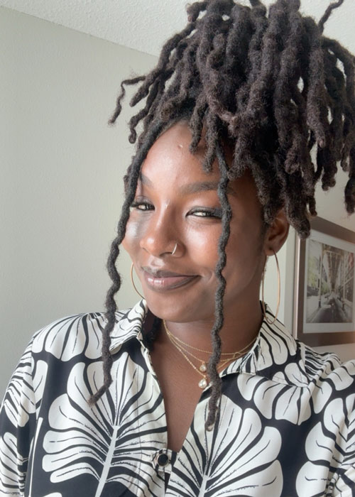 A photo of a woman with dreadlocks smiling.