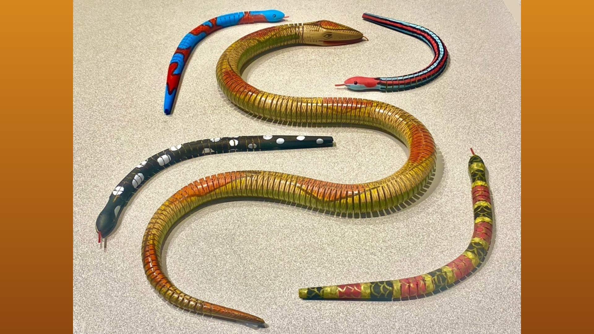 5 colorful snakes with different patterns laid out to emulate an "s" on top of a table