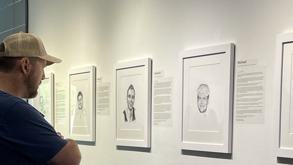 A man viewing black and white posters on a wall.