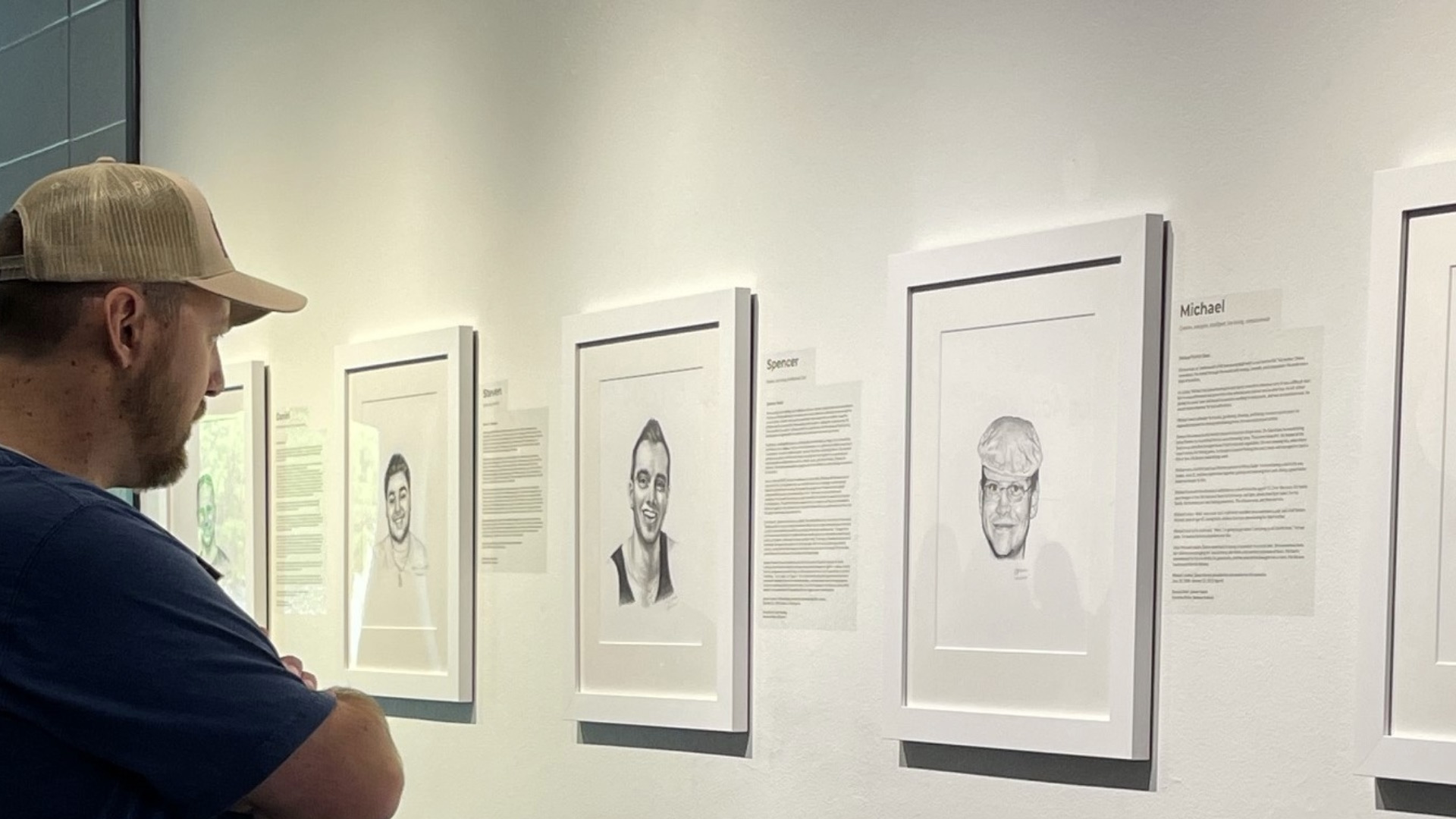A man viewing black and white posters on a wall.