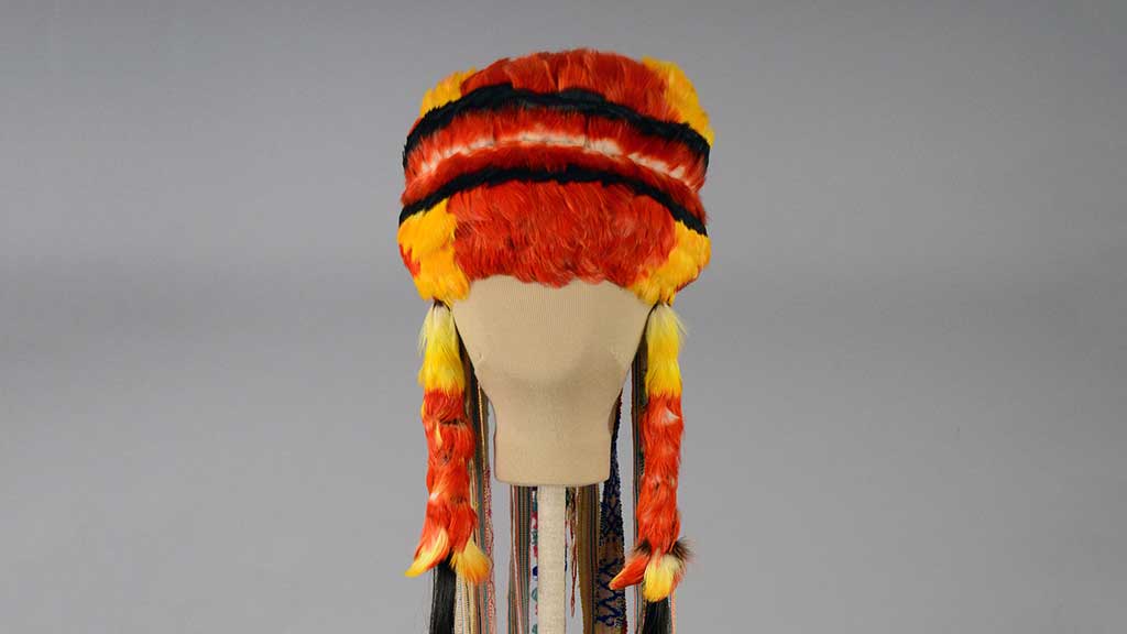 red and yellow flat hat-shaped headdress with two long vertical pieces on the sides