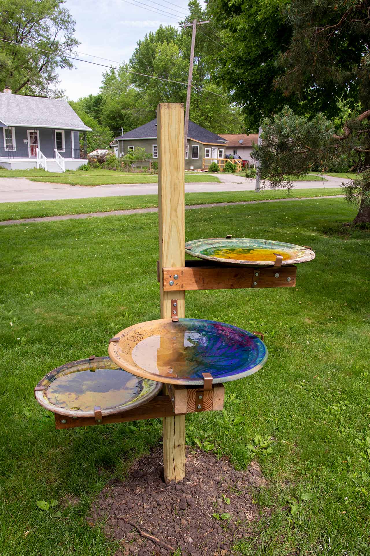 Three colored plates holding water placed on a wooden stick