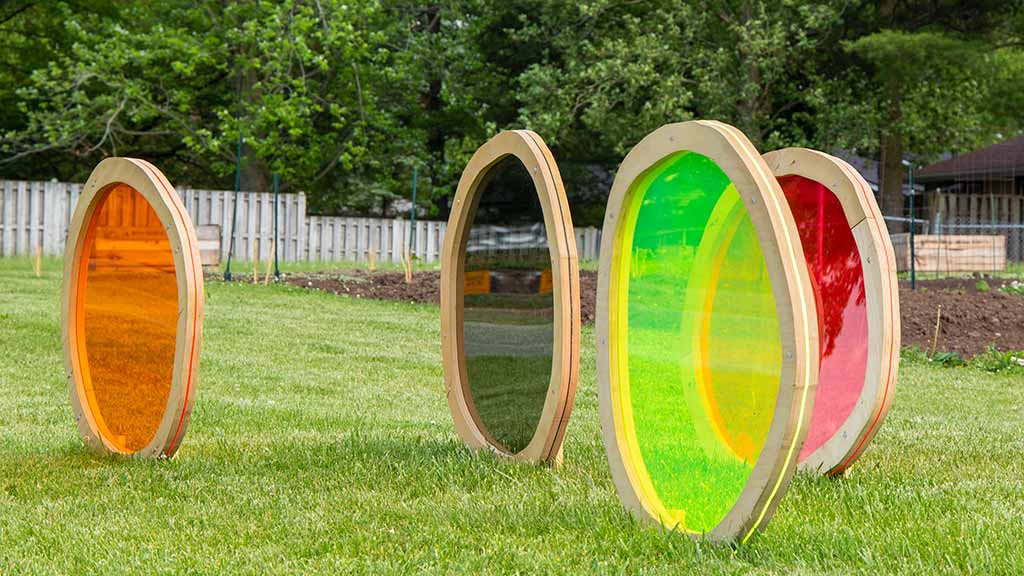 Three neon-colored and one black ellipses with wooden borders arranged in a crisscross pattern on the grass
