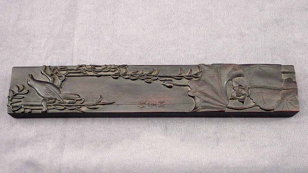long metal weight with bird and plant design