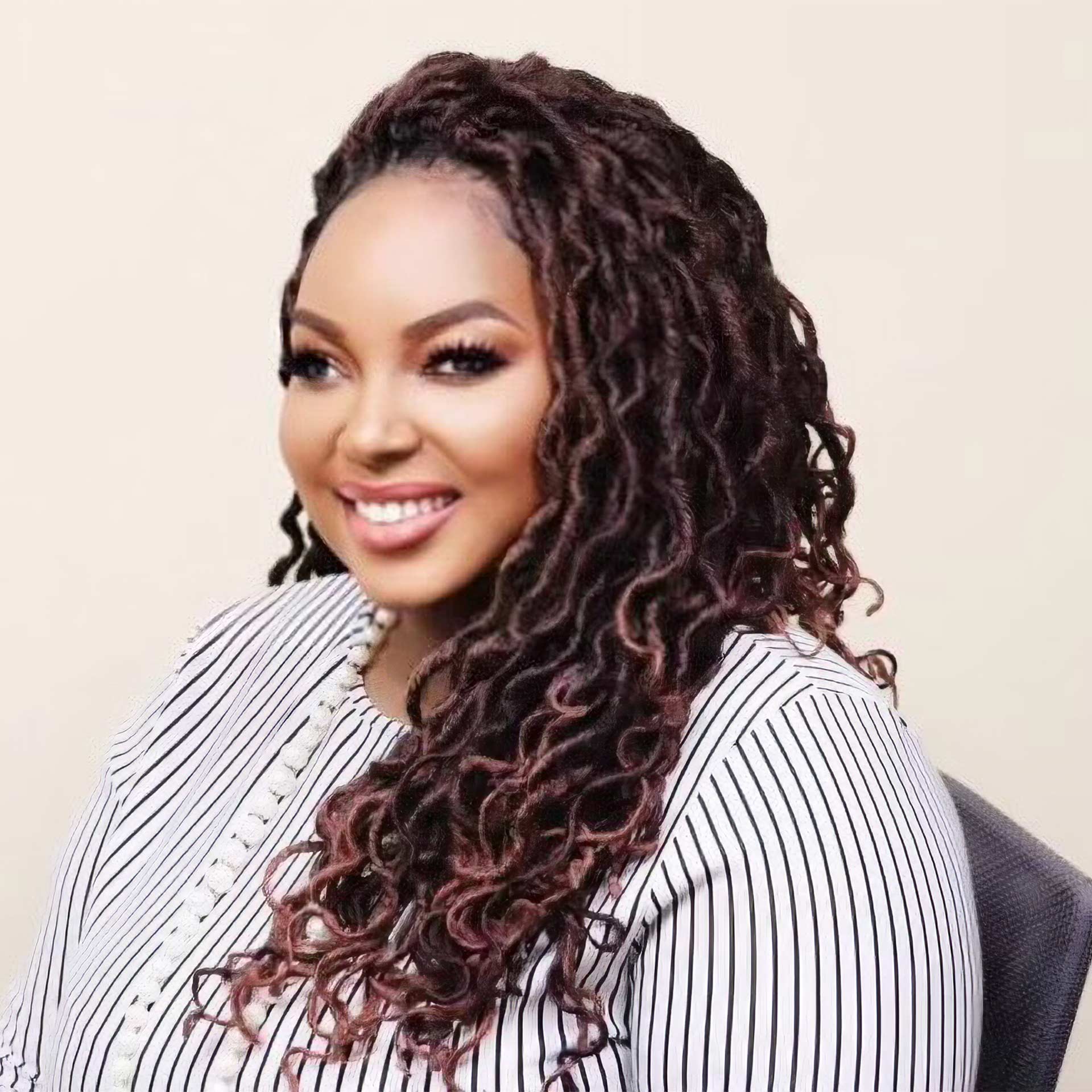 headshot of a Black woman with white striped blouse in a studio setting