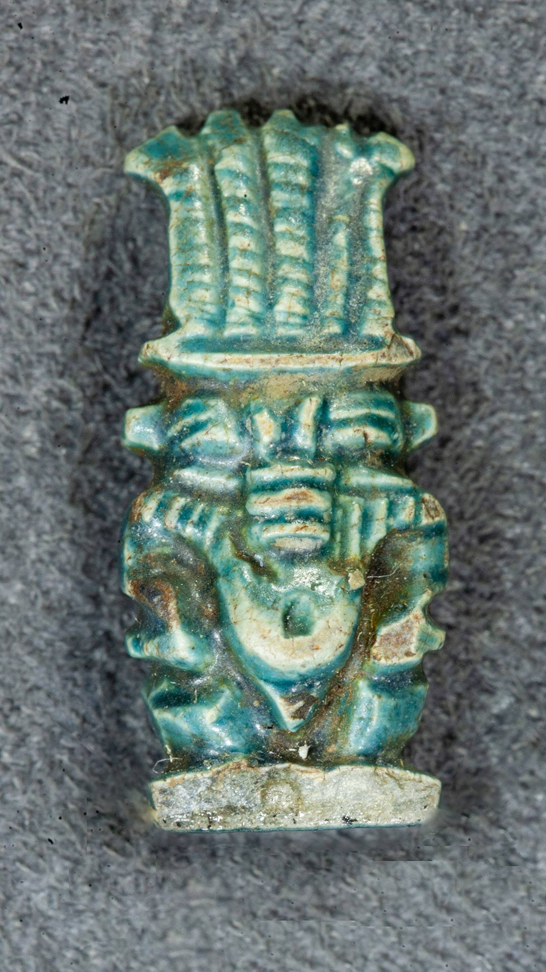 figurine of God Bes, the figurine shows the short stature of Bes and he is wearing an ostrich feather headress
