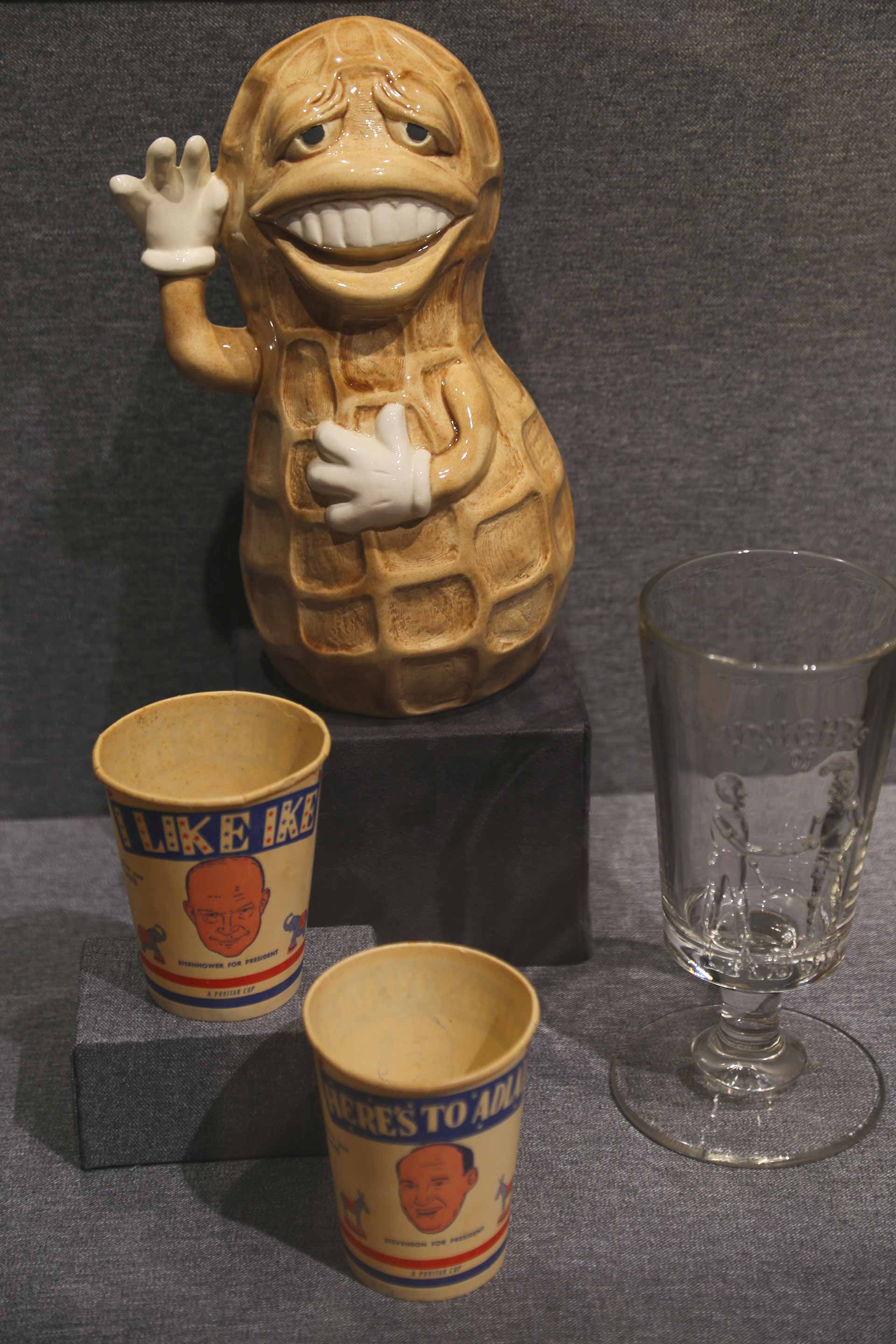 image of a peanut, a glass cup, and 2 paper cups