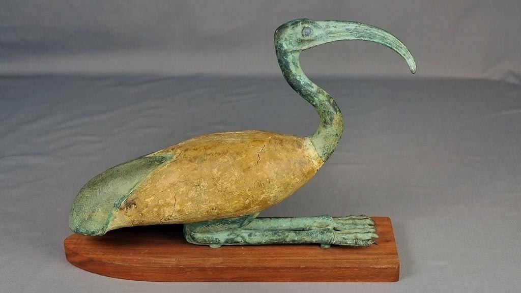 bronze statue of an ibis with green patina and yellow pigment