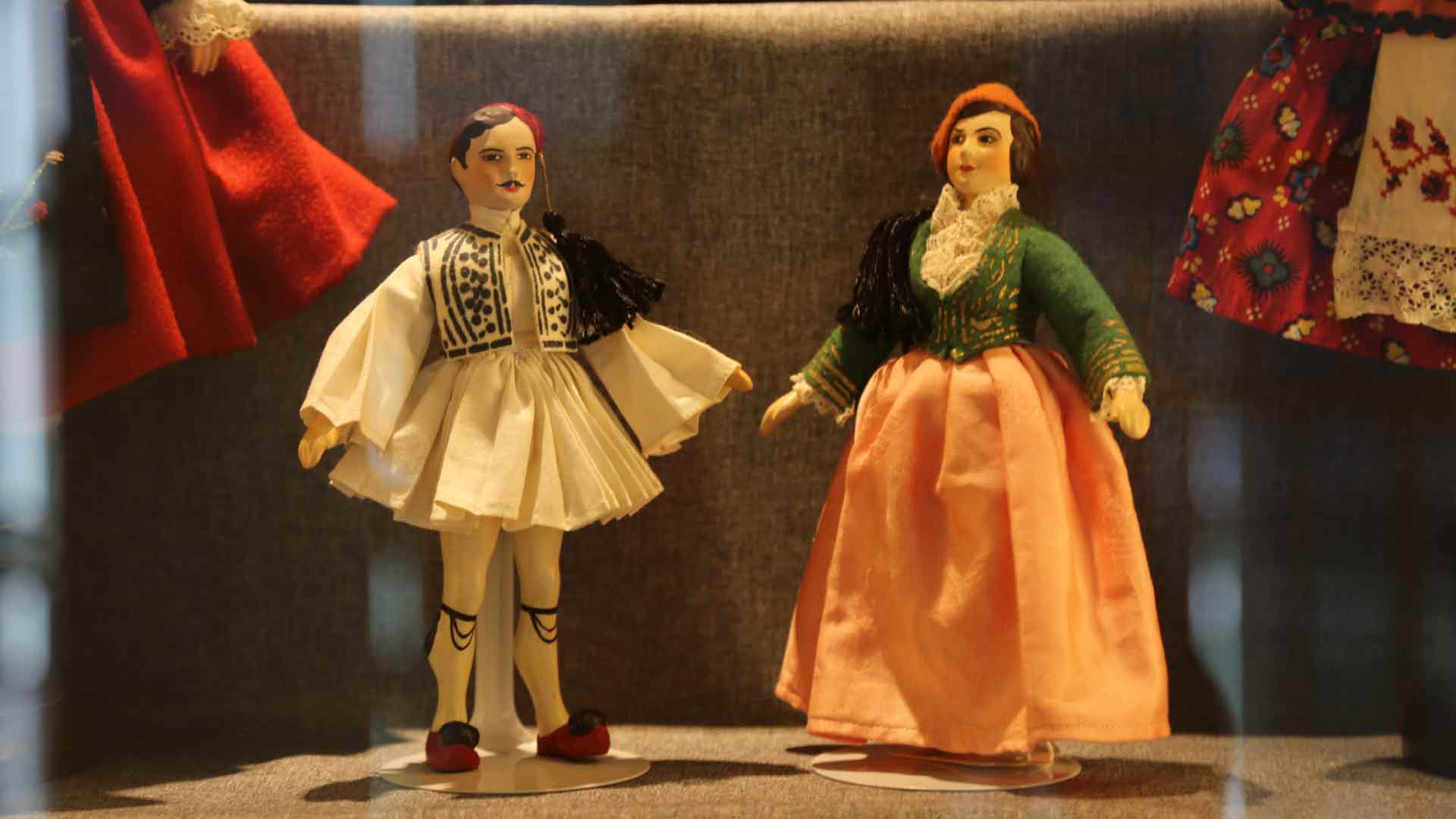 pair of dolls, a male wearing white, and a female doll wearing an orange dress