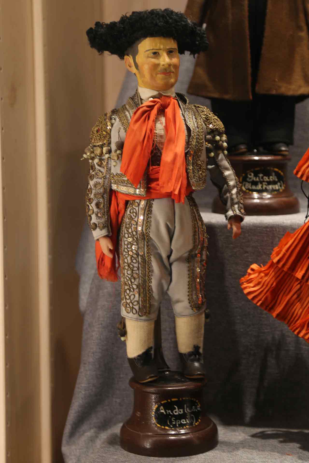 Male doll from Spain wearing gray trousers and coat, with a hat