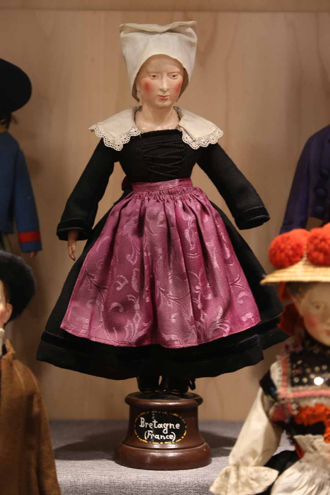 Female doll wearing black and purple dress. labelled Bretagne (France)