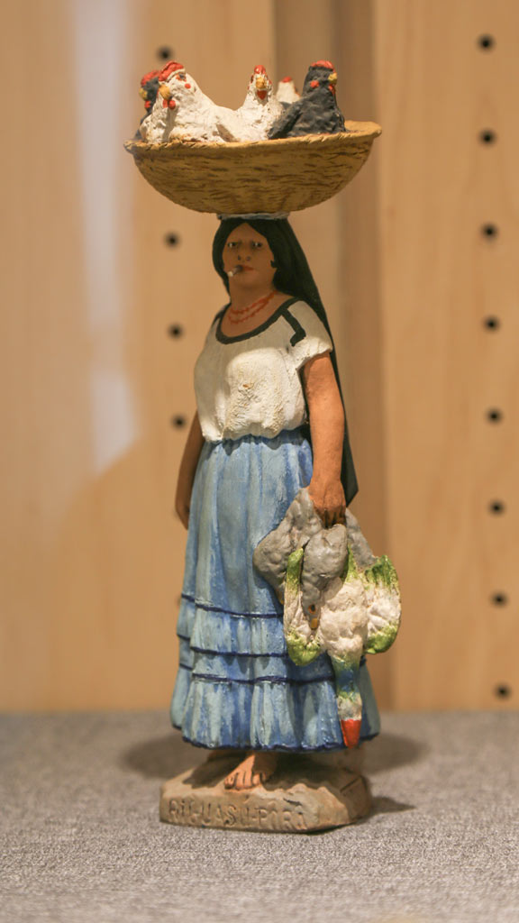 a figurine of a woman with a basket of chickens on her head