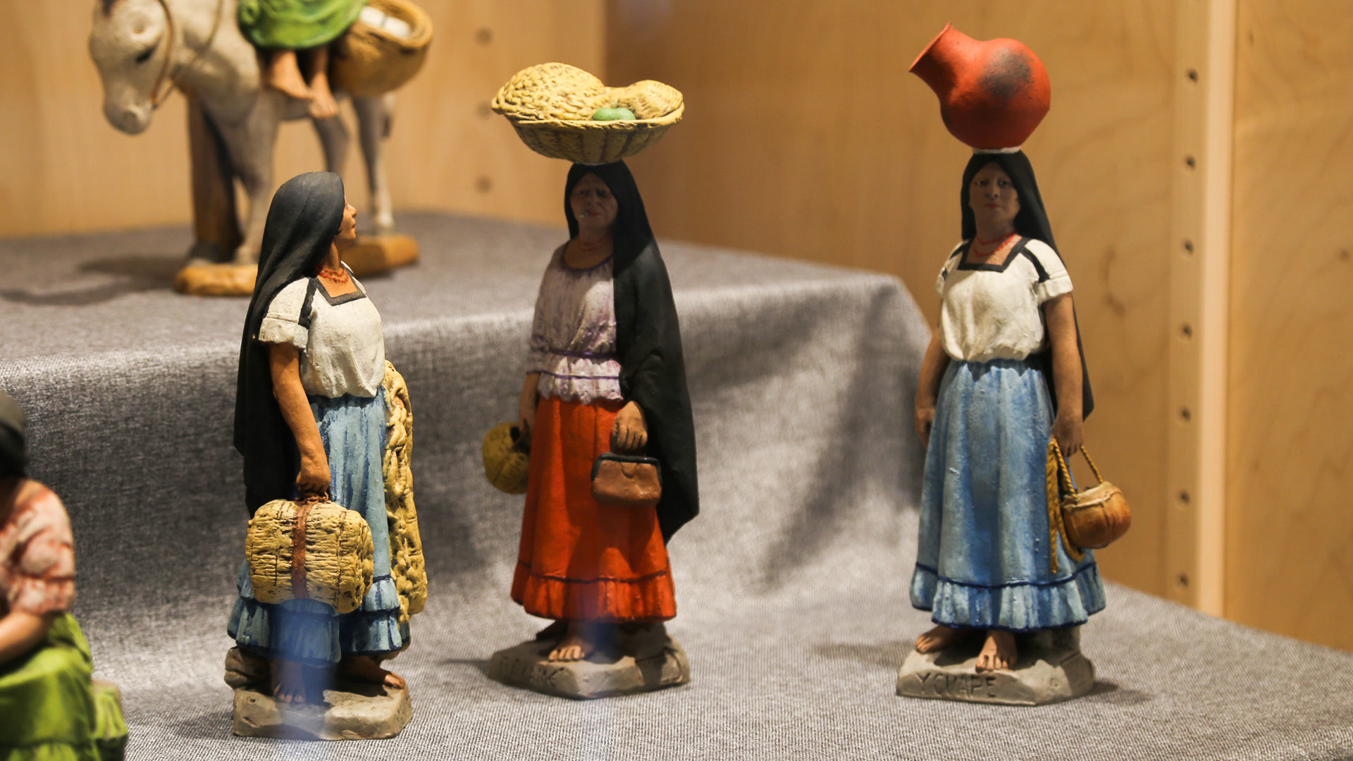 A figurine of a woman holding a basket, a figurine of a woman with a basket on her head, and a figurine of a woman with a pot on her head