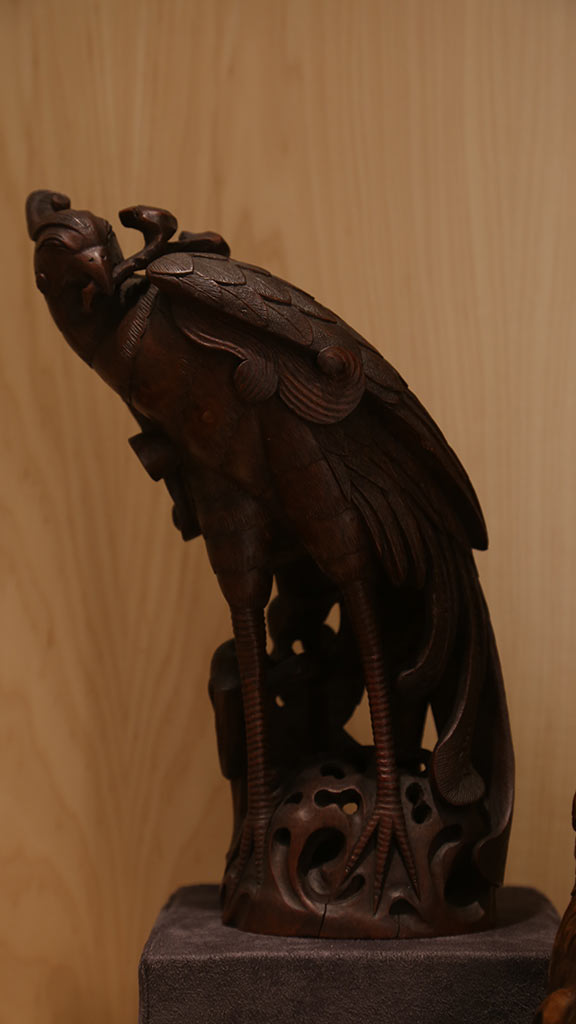 close-up of a bird-like figure holding something in its mouth