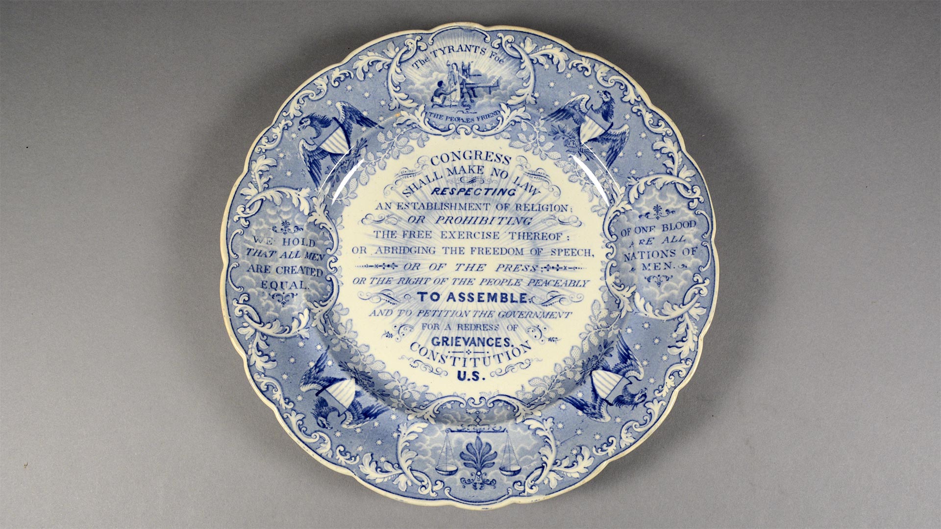 blue and white china plate with a decorative motif listing the first amendment to the US Constitution