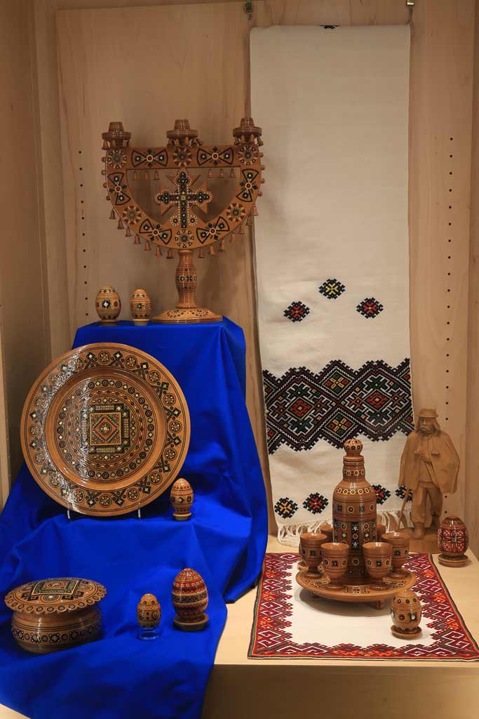case shot including Hutsul wooden dishware, a statue of a man, and an embroidered textile