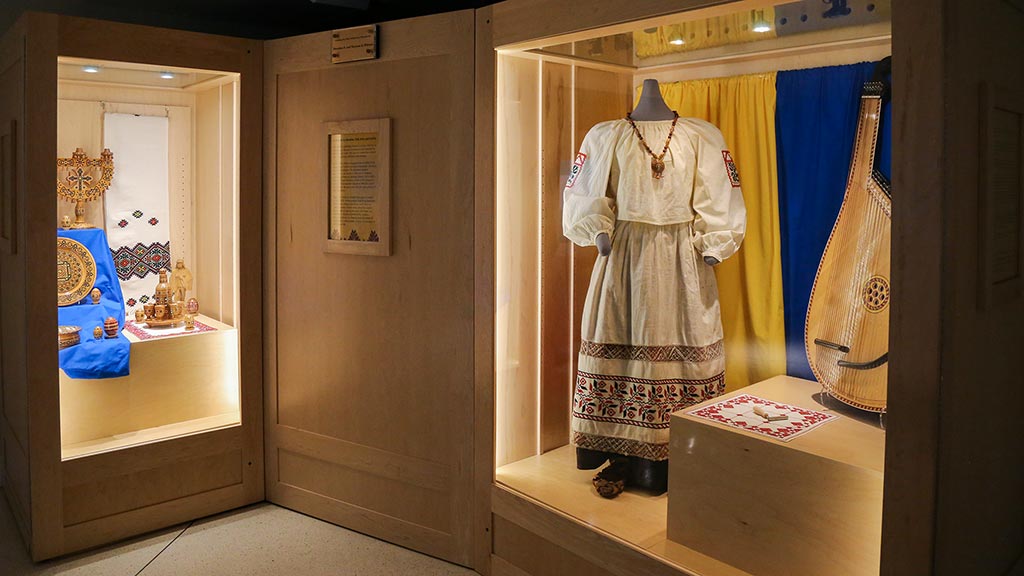 overview of exhibit with a case of wooden eggs and other objects on left and a dress on right