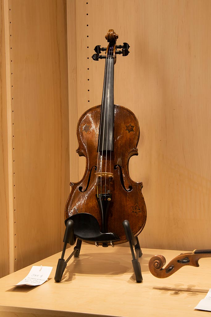brown violin displayed vertically on a violin stand
