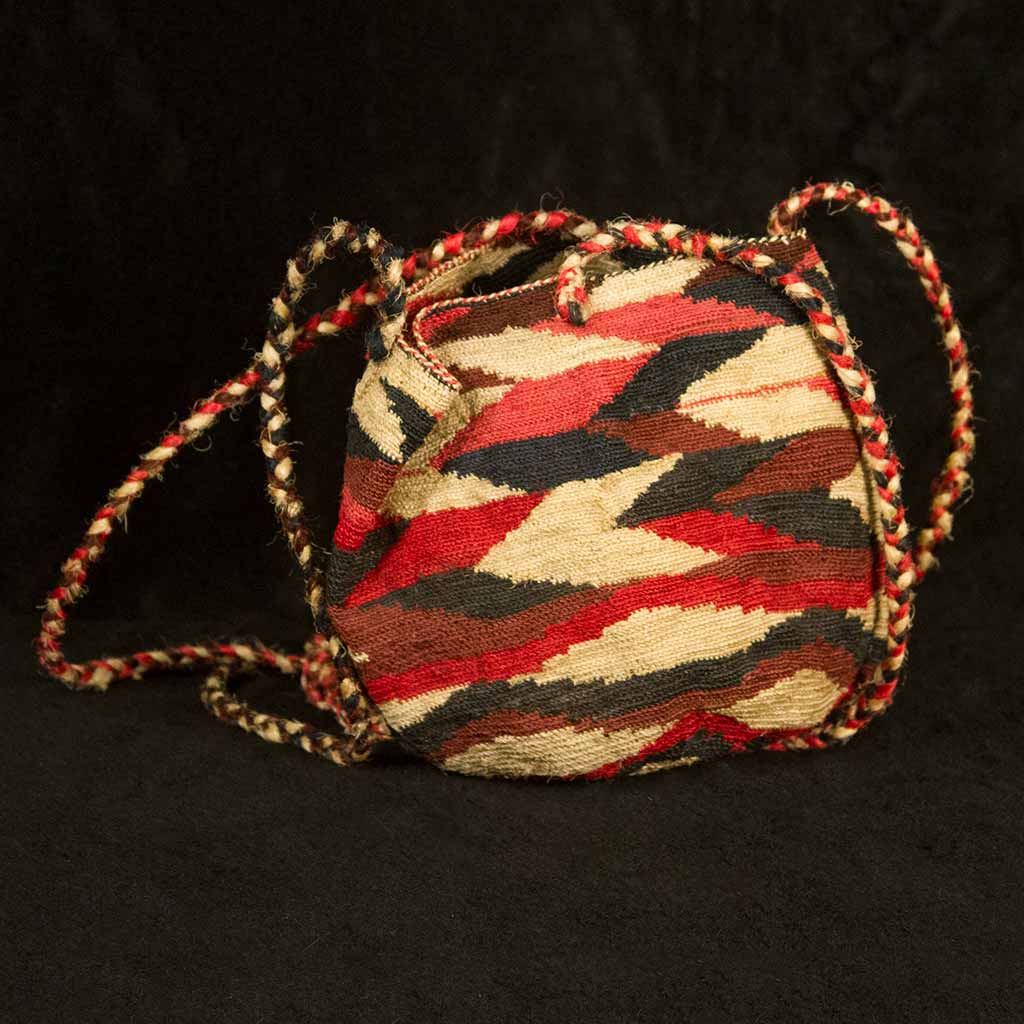 woven bag with strings and red, tan, and block geometric pattern