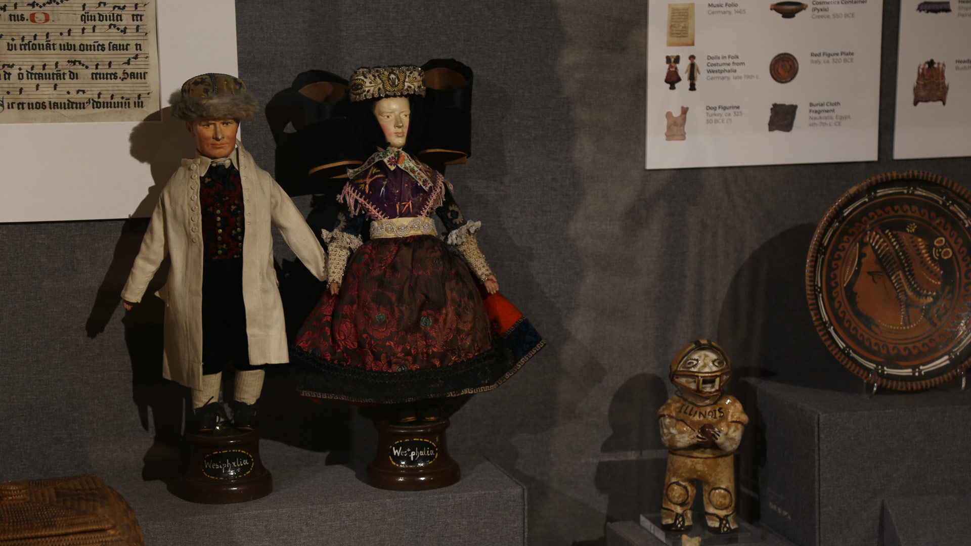 two dolls holding hands next to another figure and plate
