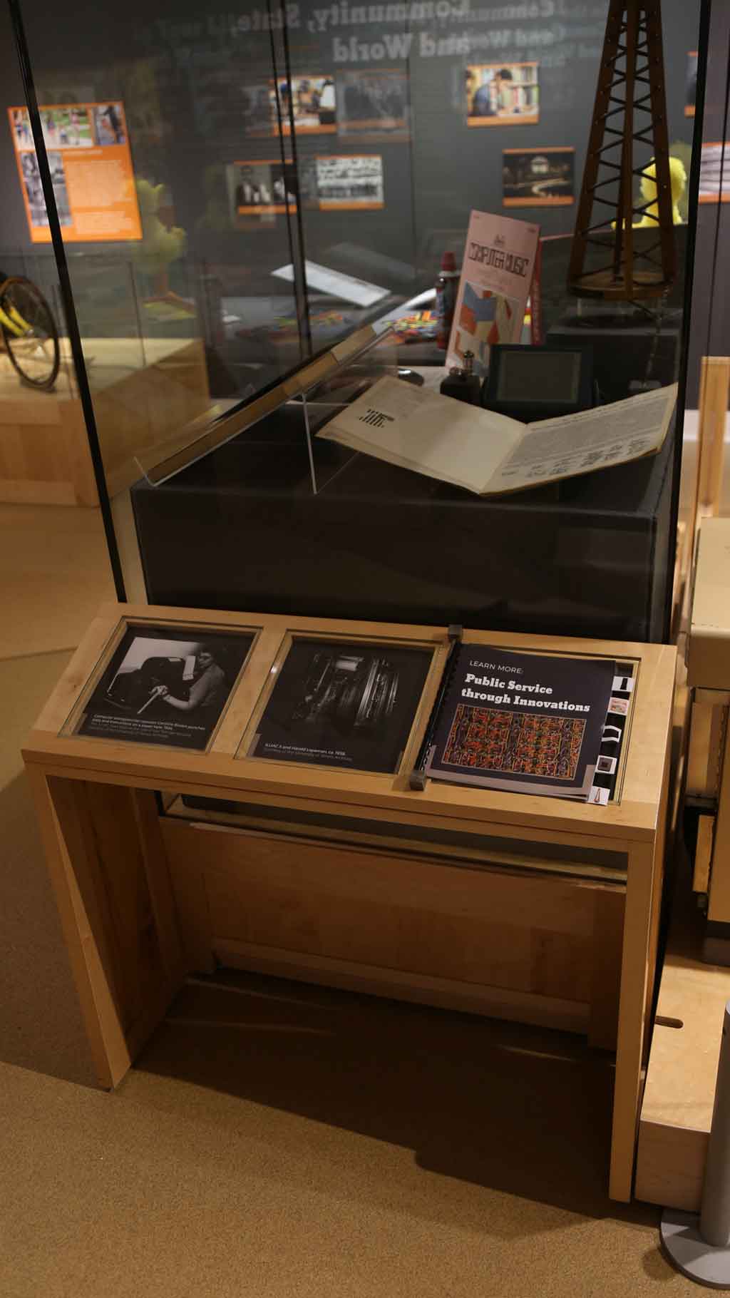 shot of a display case containing a tower looking structure and two books. An info book by it reads 'public service through innovation'