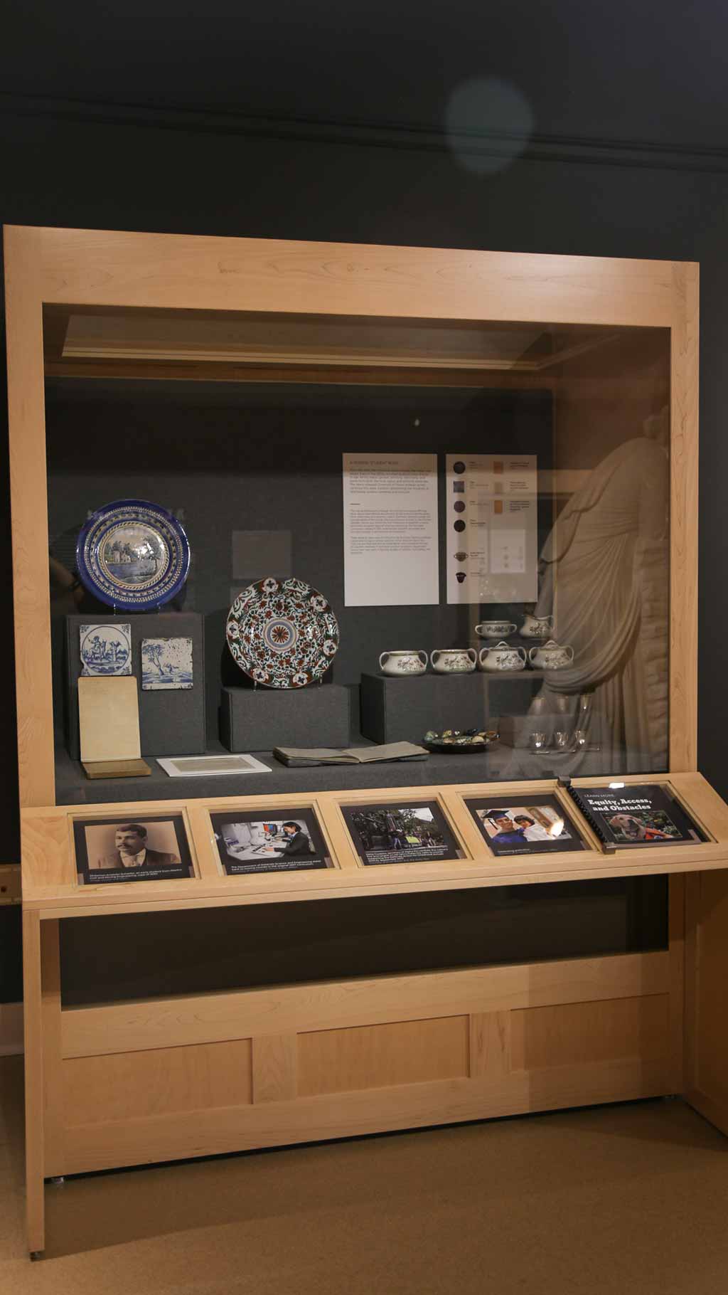 display case with decorative plates, some pots, and a book