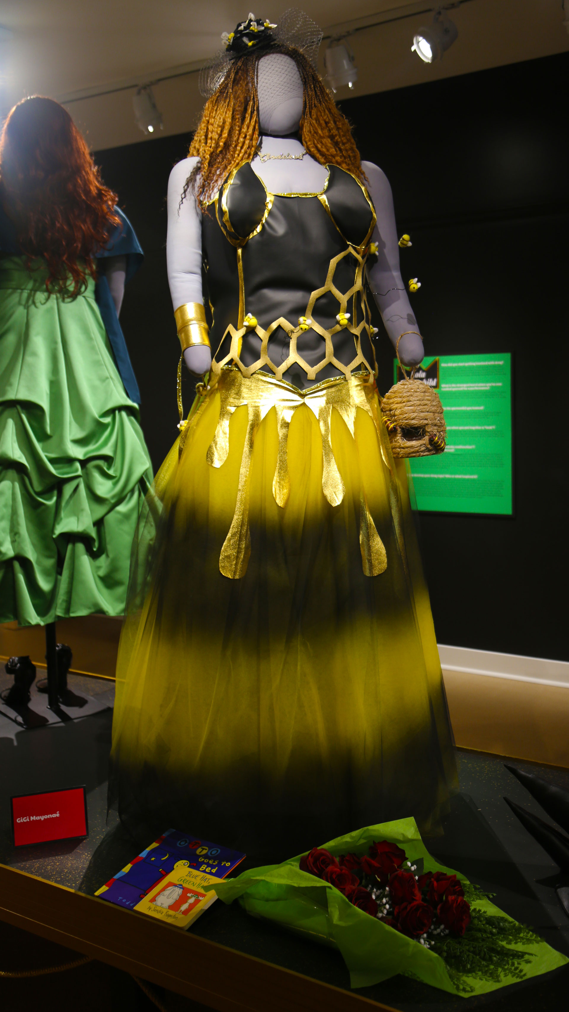 full view of mannequin in a black and gold costume with gold foil and bees attached