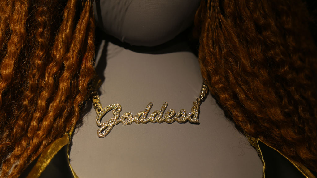 closeup of mannequin's neck with necklace that says Goddess