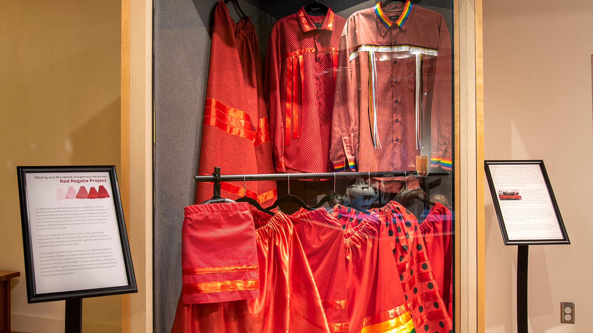 Missing and Murdered Indigenous Relatives Red Regalia Project in a bold black and red font with red skirts in different opacity on a white background