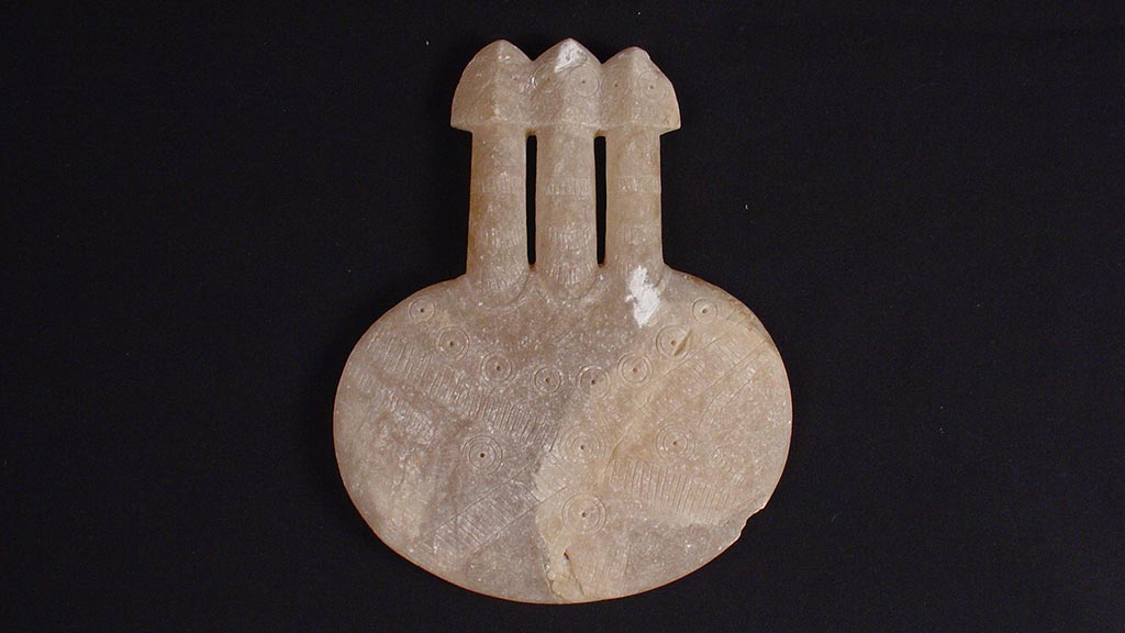 flat oval shaped stone with three stylized figures projecting from the top