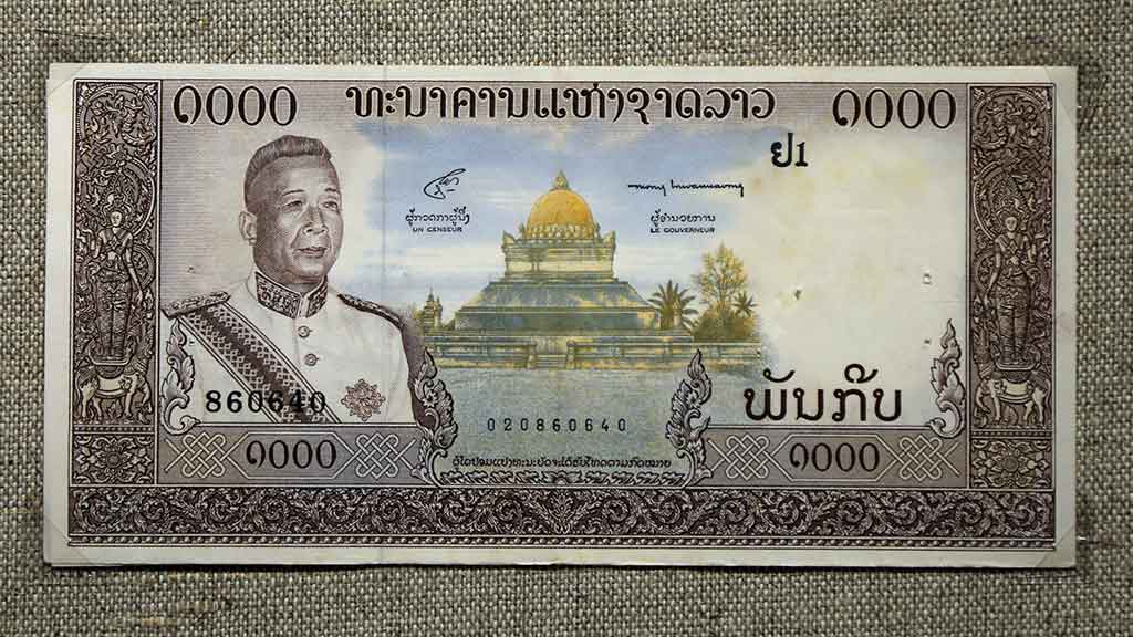 paper bank note showing Lao king and Buddhist stupa