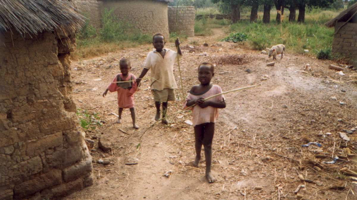 three children in the village with a pig