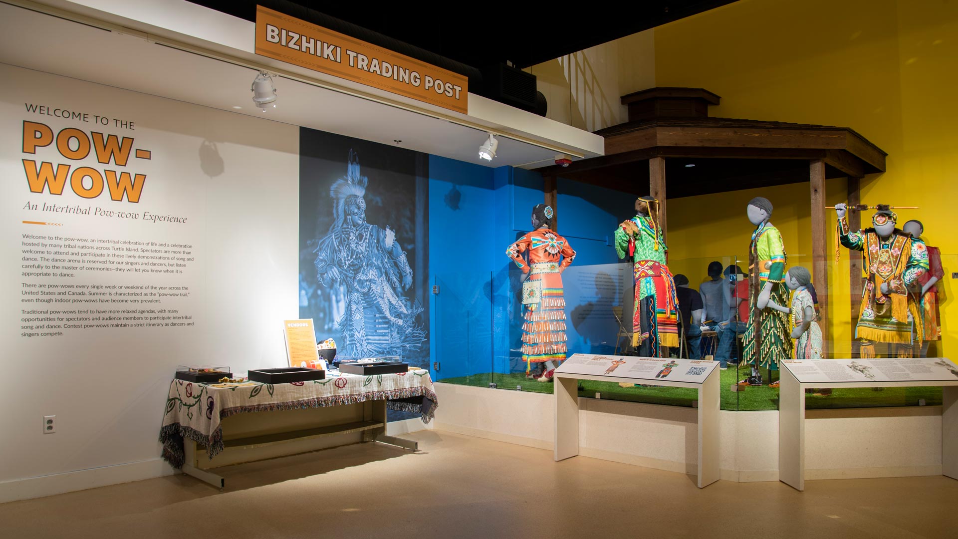 Two american indian costumed dancers in motion with Welcome to the pow-wow text on a beige background