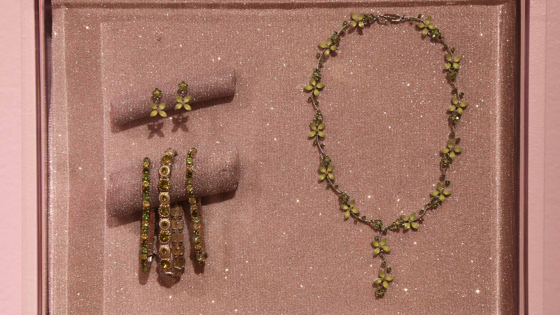 closeup of jewelry with green gems including a necklace, bracelets, and earrings