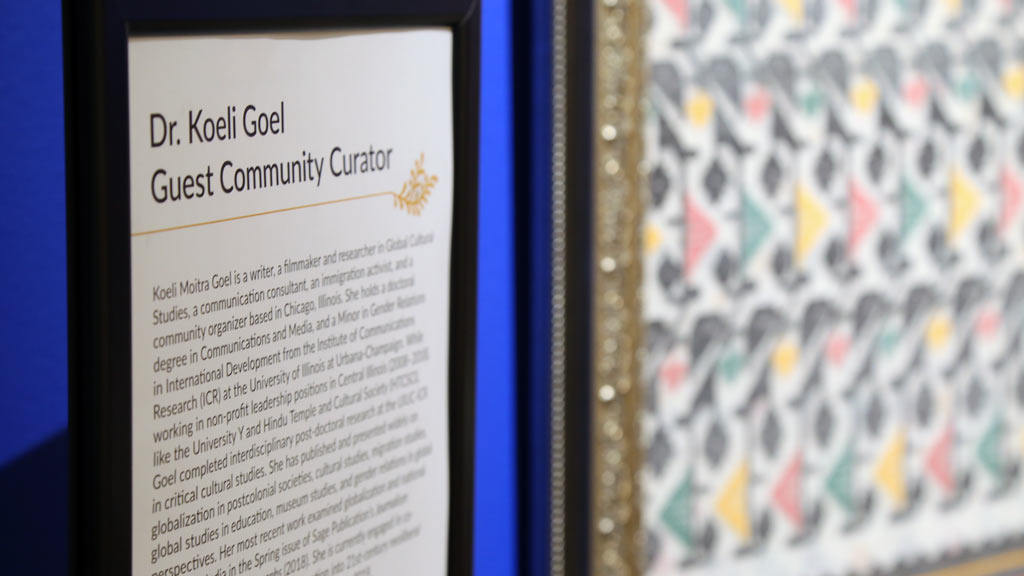 angled close-up of text next to the textile reading 'Dr. Koeli Goel Guest Community Curator'